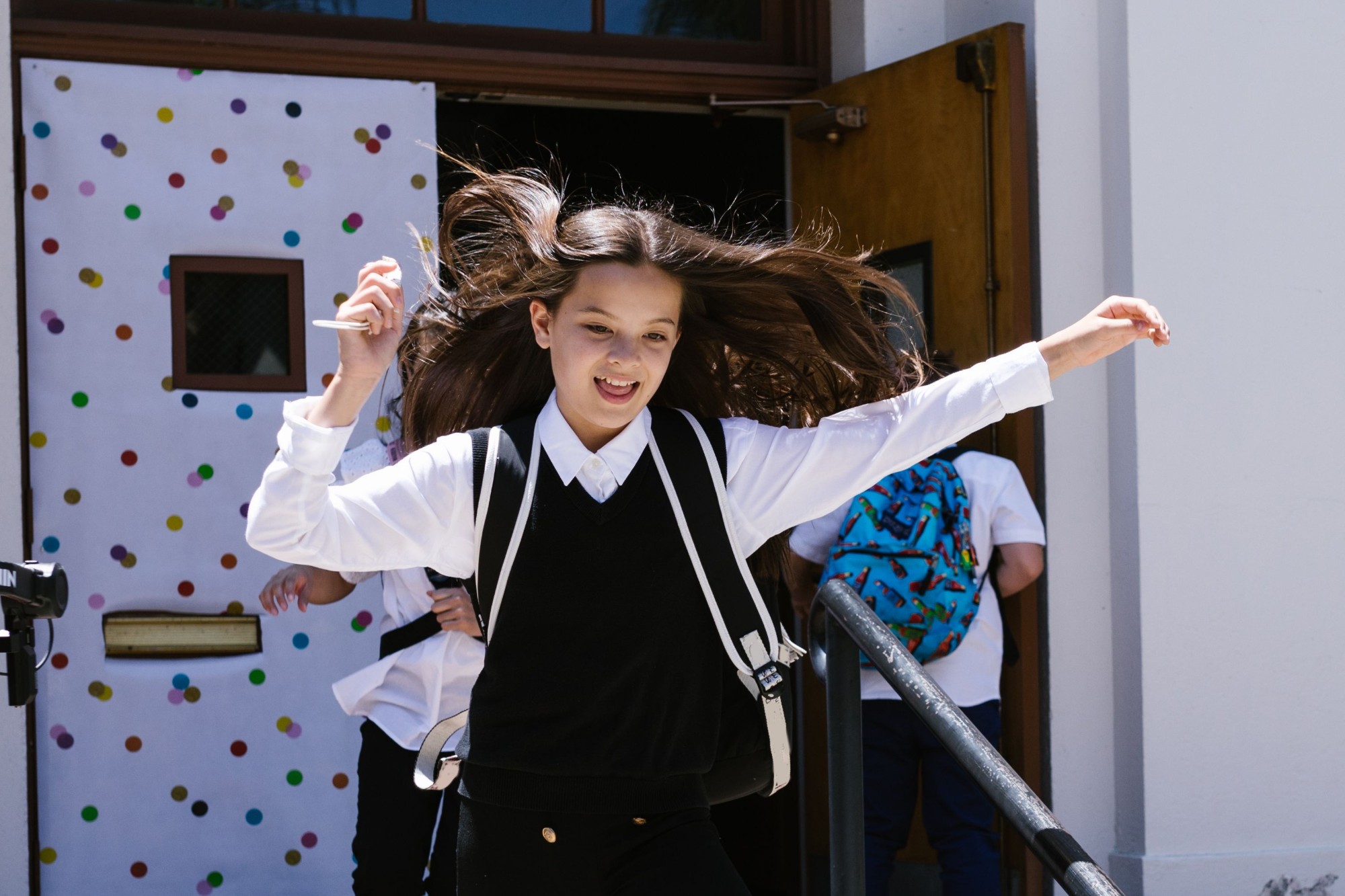 Child in school uniform walking through school gates