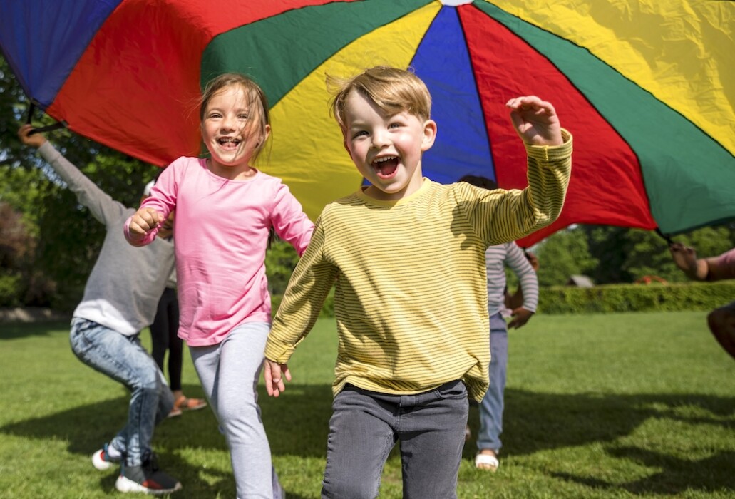 Kids playing with a rainbow parachute at King Edward's School adventures holiday camp in Bath